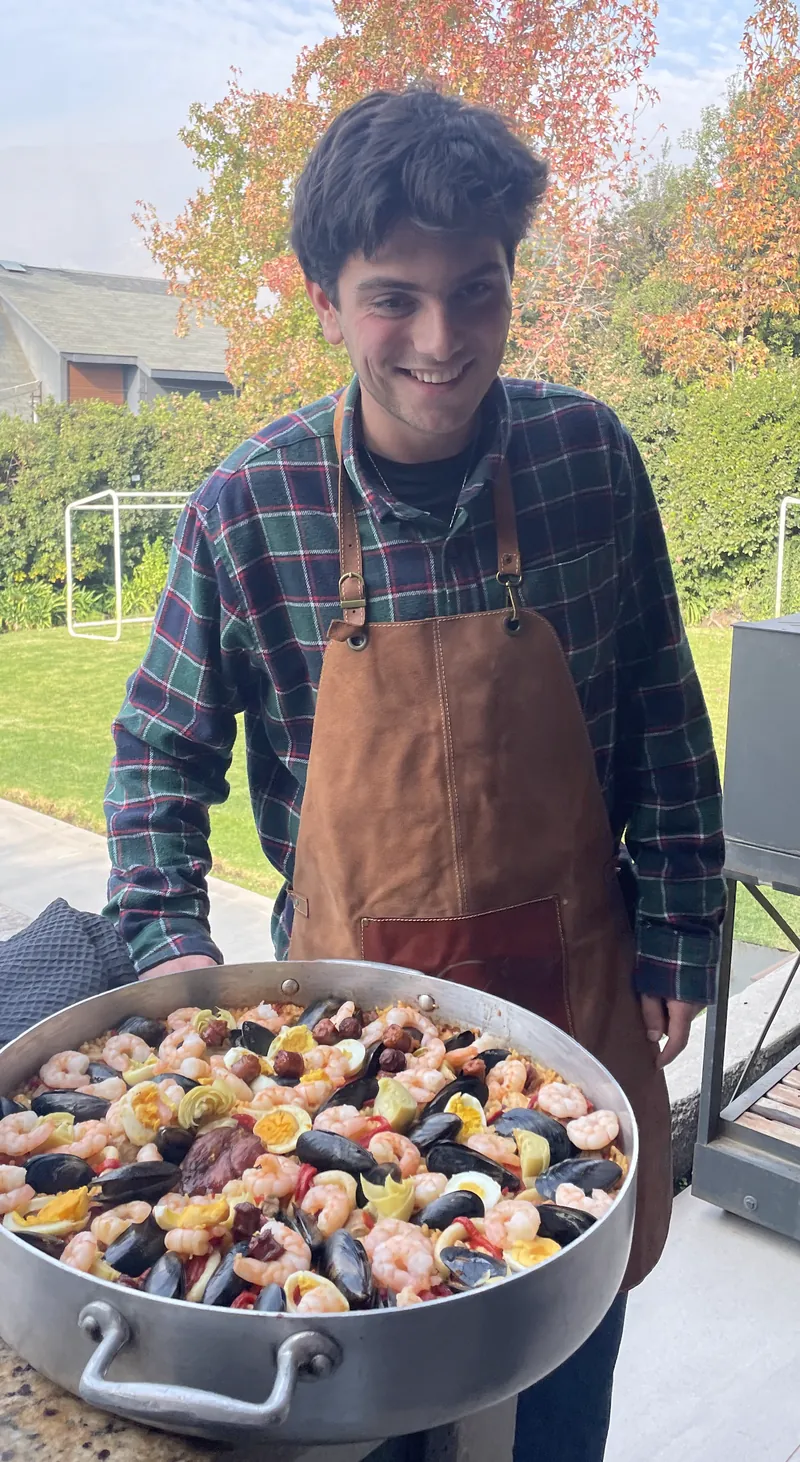 Joaquín, fundador de Kanpotar Etxea, sonriendo detrás de una paella en el jardín de una casa